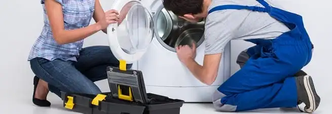 Washer repair technician inspecting a front-load washing machine with tools in Chicago, IL