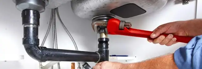 Garbage disposal repair technician tightening the sink drain and disposal connection in Chicago, IL