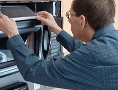 Appliance repair technician replacing a microwave vent filter in Chicago, IL