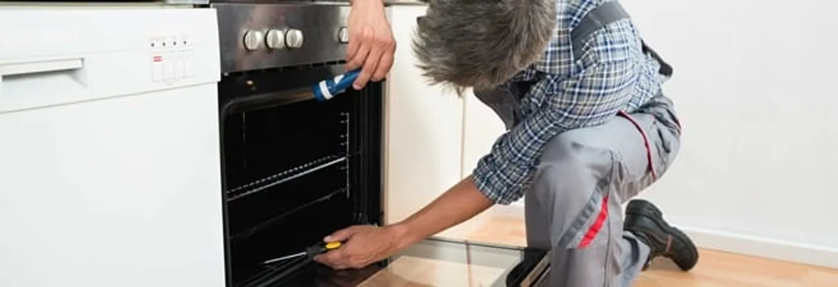 Oven repair technician inspecting and servicing an electric oven in Chicago, IL