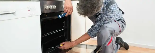 Oven repair technician inspecting and servicing an electric oven in Chicago, IL