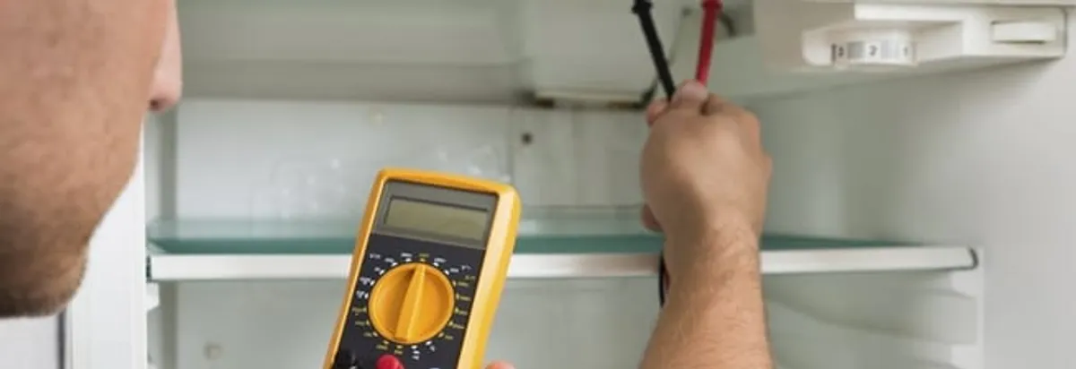 Refrigerator repair technician testing electrical components with a multimeter in Chicago, IL