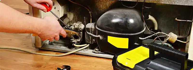 Refrigerator repair technician fixing the compressor and wiring in Chicago, IL