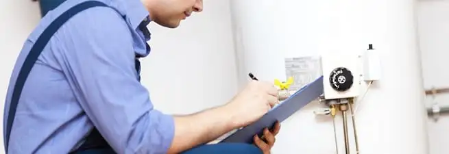 Water heater repair technician inspecting the unit and recording service notes in Chicago, IL