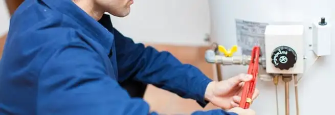 Water heater repair technician adjusting the temperature control and gas valve in Chicago, IL